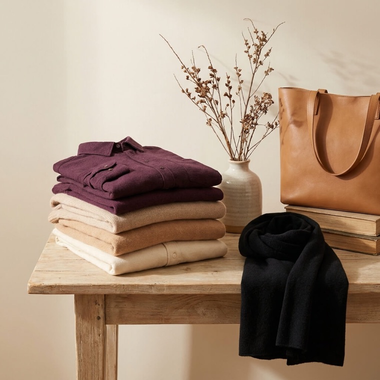 Neatly folded shirts and jumpers stacked by colour